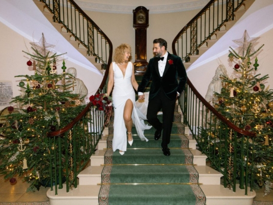 A joyful couple walks down a decorated staircase.