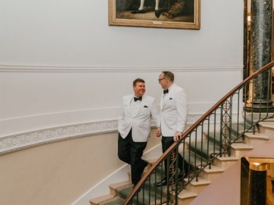 Formal gathering with men in tuxedos on a grand staircase.