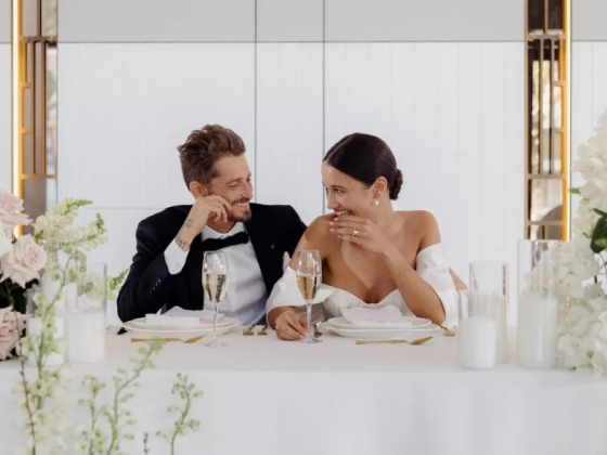 Smiling couple shares a joyful moment at their wedding table.