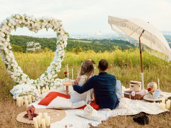 Couple enjoying a picnic with a proposal backdrop.