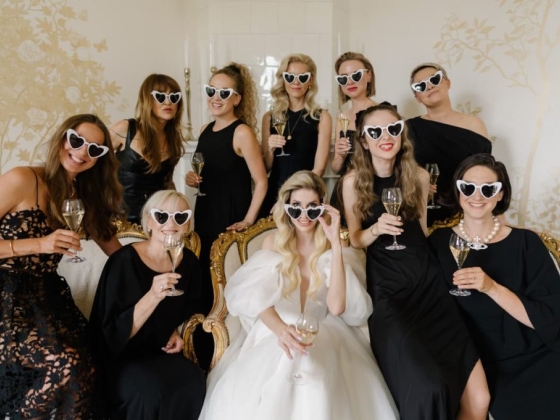 Bridal party celebrating with drinks and heart sunglasses.