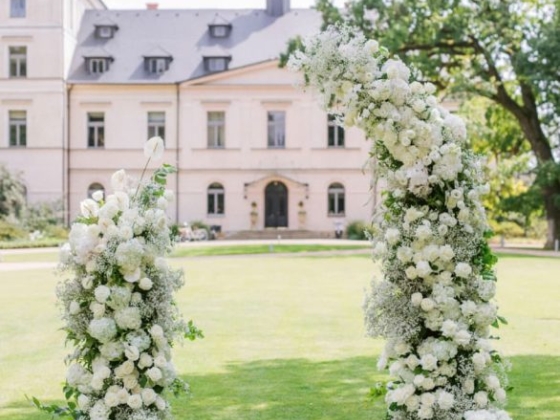 Beautiful white flower arch in a lush outdoor setting.