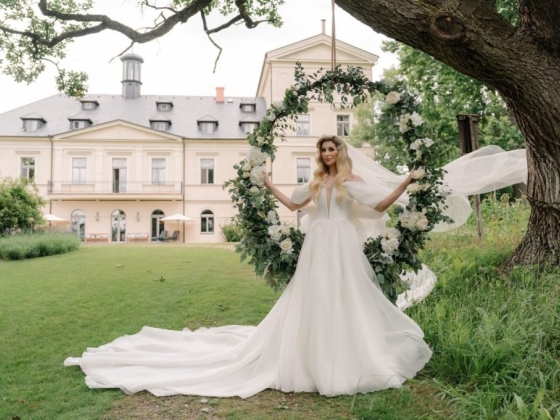 Elegant bride poses with floral arrangement and a historic building in background