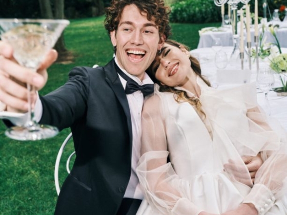 Joyful couple sharing a toast at an outdoor wedding.