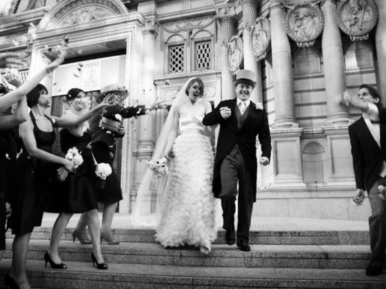 A joyful wedding moment on the steps of an elegant building.
