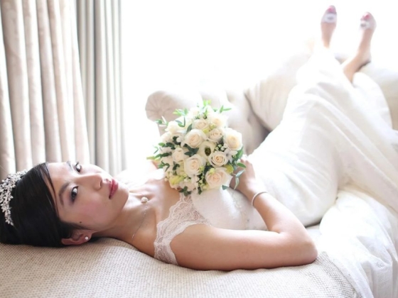 A serene bride resting on a sofa, holding a bouquet.
