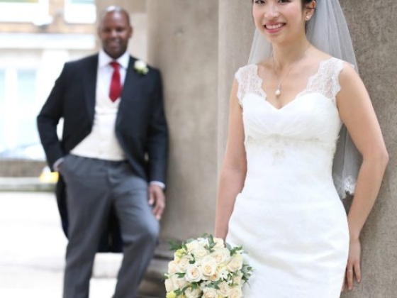 A joyful bride poses with her bouquet as the groom stands behind.