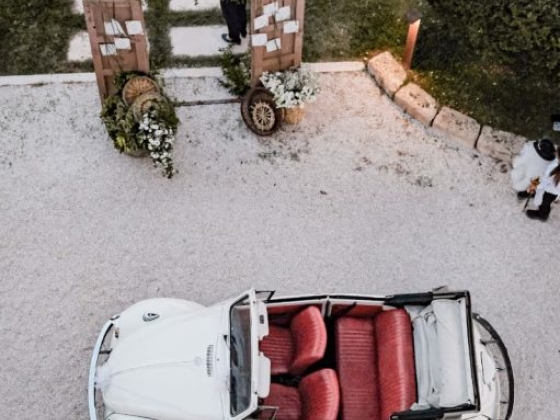 A white convertible parked in a picturesque garden.
