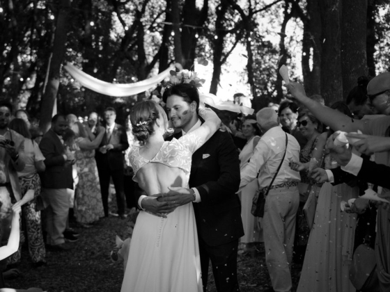 Newlyweds share a joyful moment while guests celebrate.