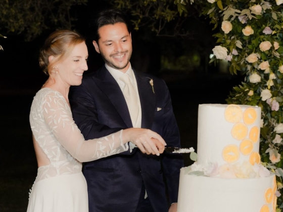 A couple joyfully cutting their wedding cake outdoors at night.