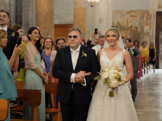 A bride elegantly dressed with her father on their way to the altar.