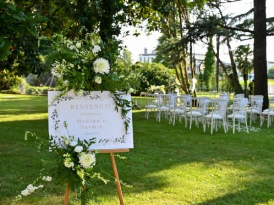 A welcome sign for a wedding in a lush garden.