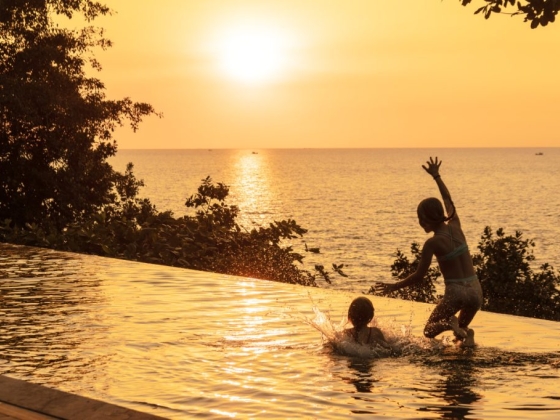 Fun moments in a pool as the sun sets over the ocean.