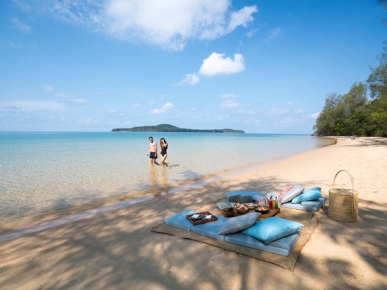 A serene beach scene featuring a couple and a picnic area.