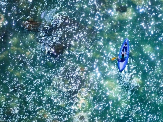 Aerial view of a kayaker on shimmering water.