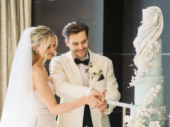 A bride and groom celebrate by cutting their wedding cake.