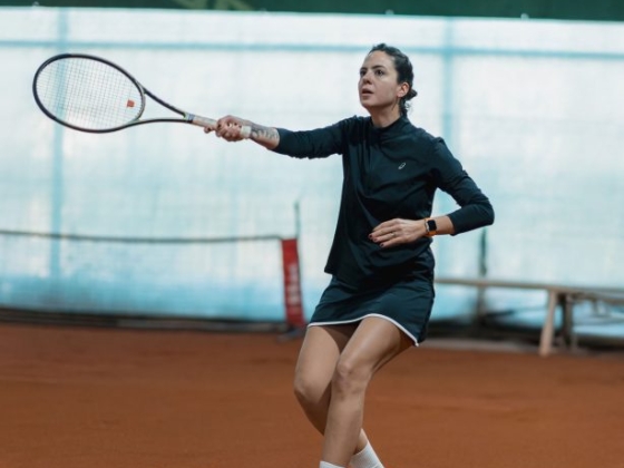 A player prepares for a tennis shot indoors.