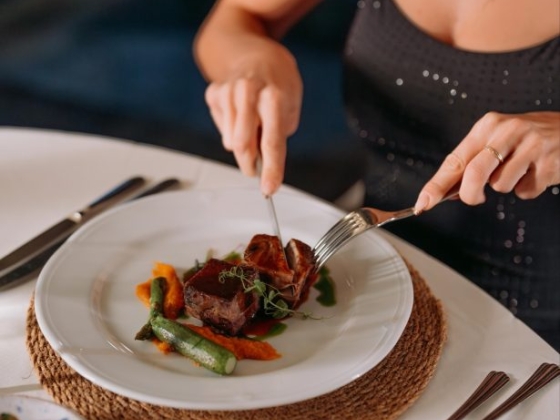A close-up of a woman enjoying a plated dish.