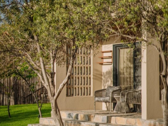 A cozy house corner with patio chairs and lush grass.