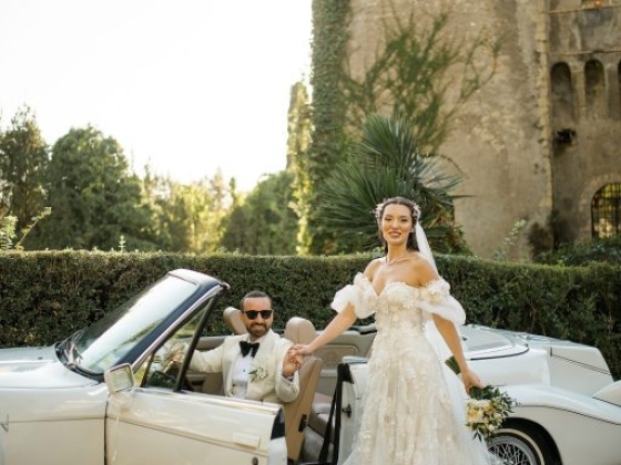 A couple celebrates their wedding by a vintage car.