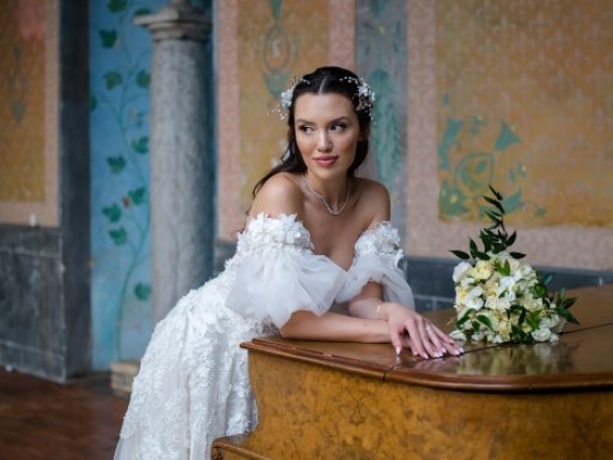A bride elegantly poses by a piano, showcasing her gown.