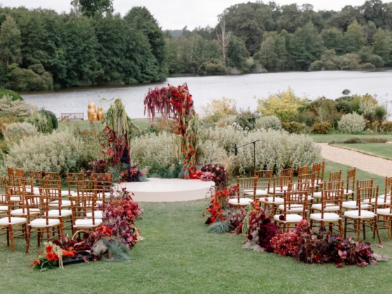 Beautifully arranged wedding chairs and backdrop by water.