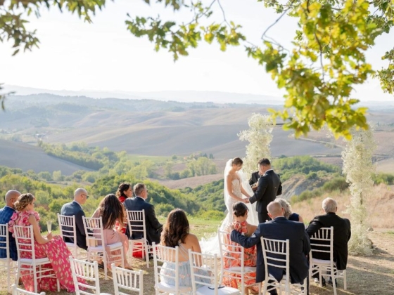 Couple exchanging vows with guests seated on a hilltop.