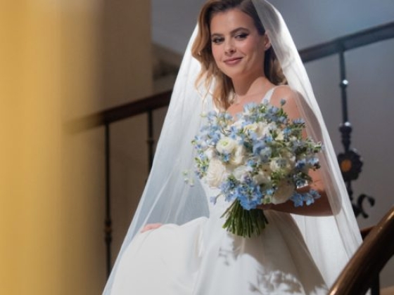 Elegant bride poses with bouquet on a staircase.