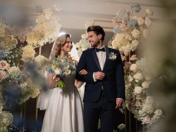A joyful couple stands amidst beautiful flowers.