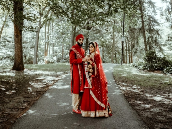 A bride and groom pose on a scenic path in a forest.