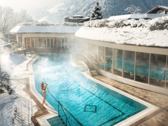 A serene outdoor pool in winter, with steam rising.
