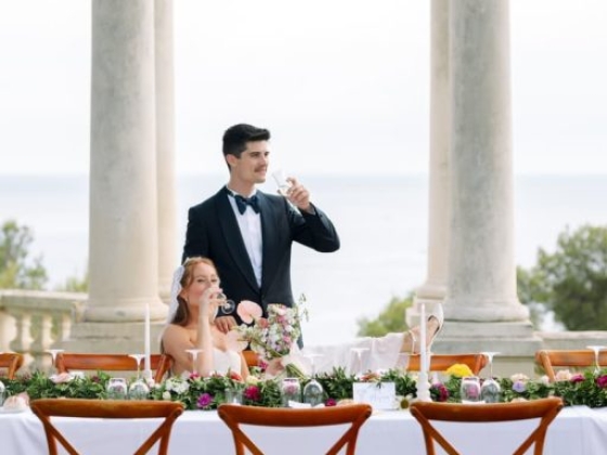 Couple celebrating with drinks at a decorated wedding table.