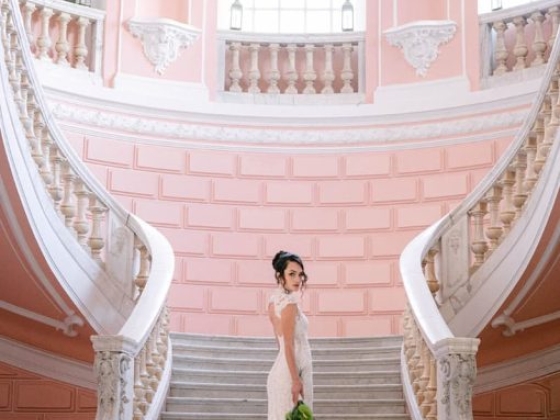 A bride poses gracefully on a grand staircase.