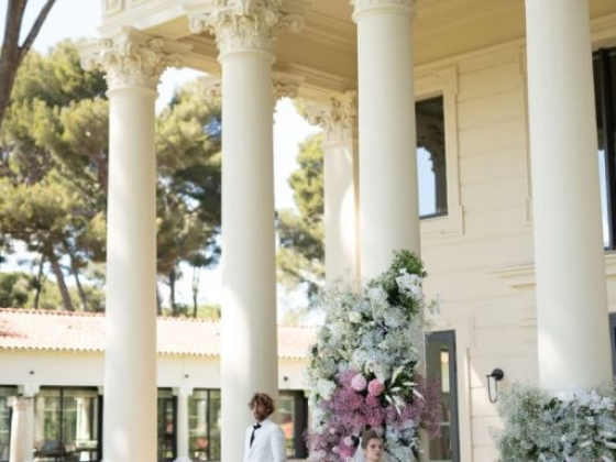 A couple poses elegantly in front of a beautifully adorned building.