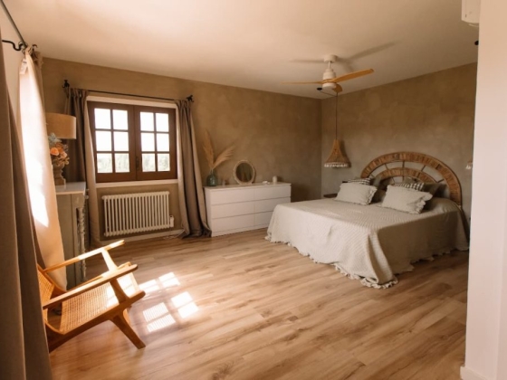 Bright bedroom featuring a wooden bed and cozy chair.