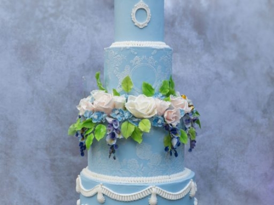A beautifully decorated blue wedding cake with flowers.