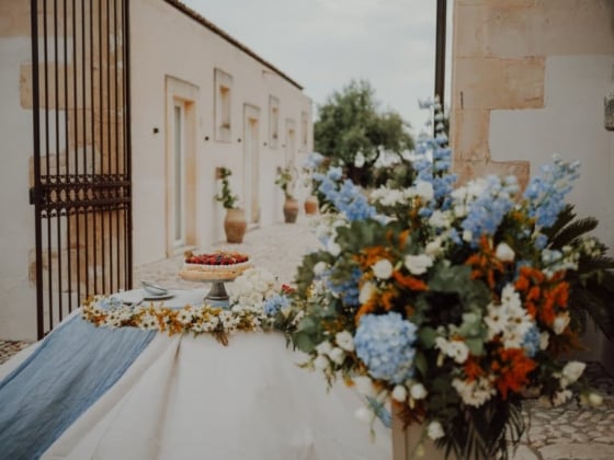 A beautifully arranged outdoor table with flowers and a cake.