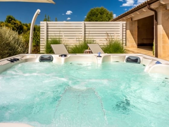 A serene hot tub view with loungers and a clear blue sky.