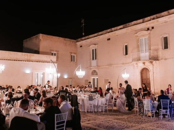 Guests enjoying a lavish dinner under chandeliers.