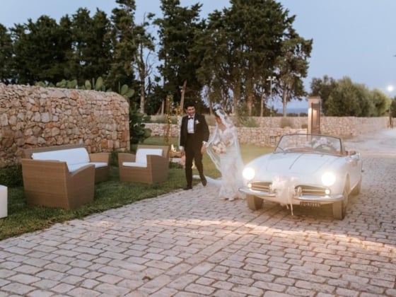 Couple strolls along a stone path by a vintage car.