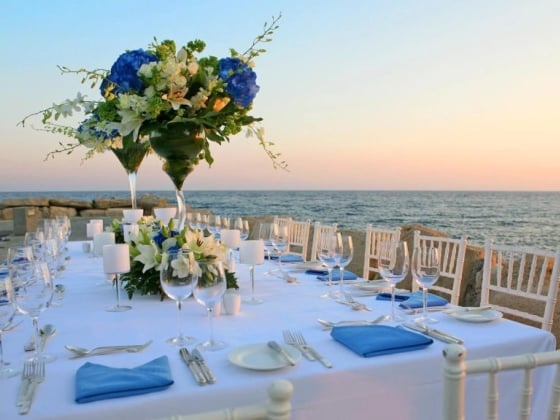 Beautifully set dining table by the ocean at sunset.