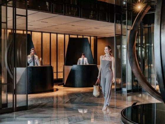 A fashionable woman enters a modern hotel lobby.