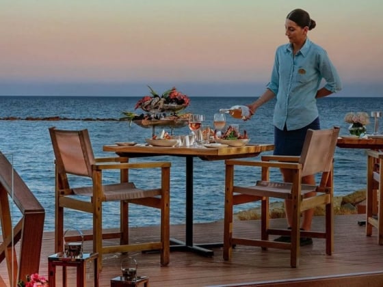 A server pours wine at a beautiful beachside table.