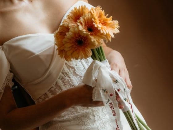 A smiling bride with flowers in her hand.