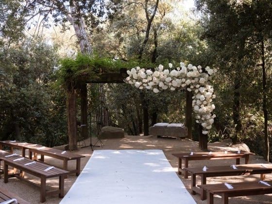 Serene venue with benches and a floral arch for a wedding.