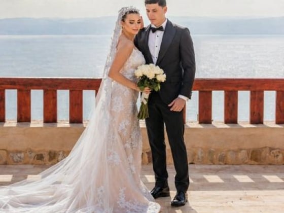 A couple poses for photos at their wedding seaside.