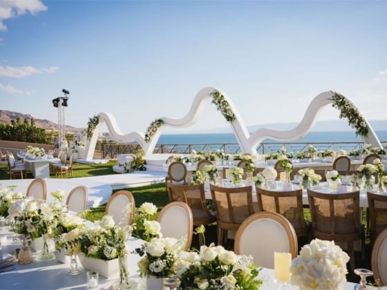 Beautiful seaside venue with tables and floral arrangements.