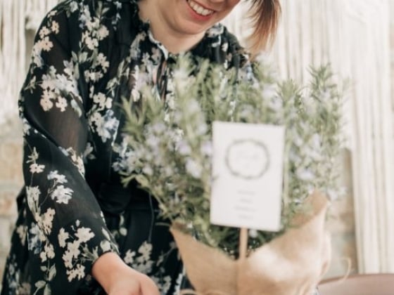A woman decorates a table with a potted plant.