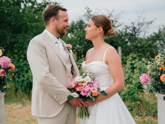 A couple stands together with floral arrangements, celebrating their wedding.