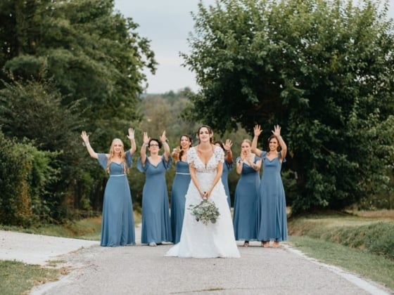 The bride stands smiling with her joyful bridesmaids.